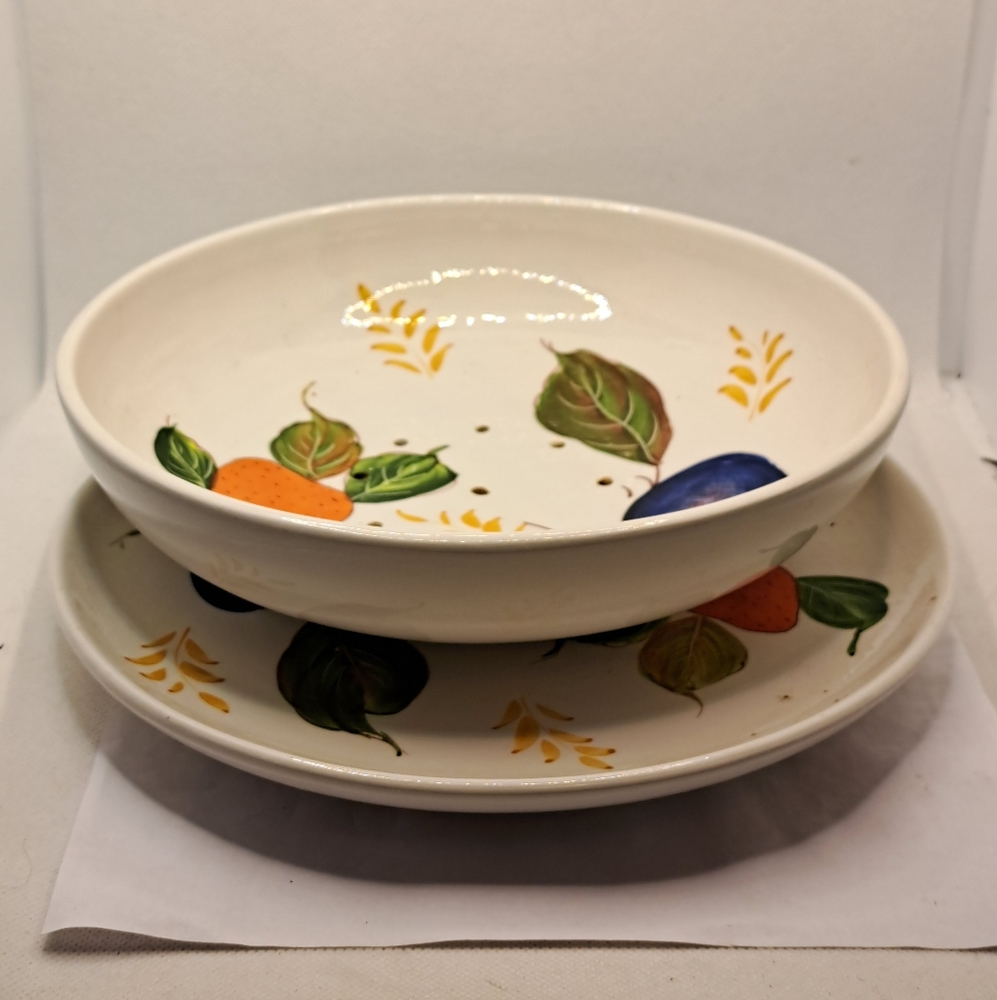 Hand painted ceramic colander made in Italy with drain holes on bowl with plate.